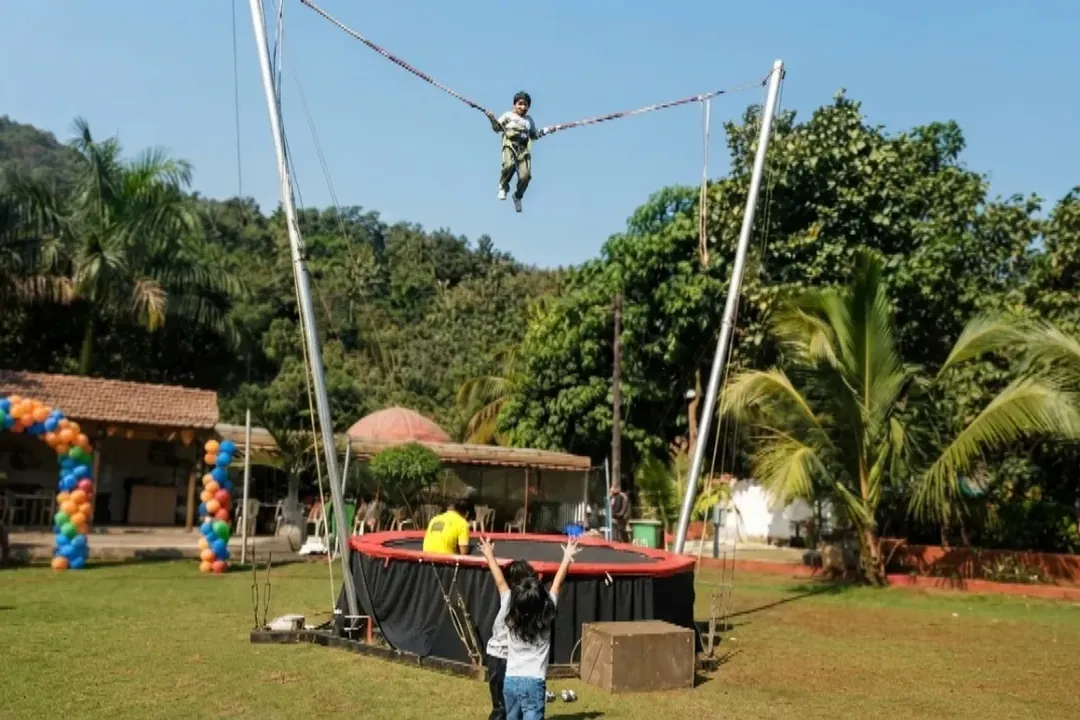 Person bouncing high on a harnessed bungee trampoline outdoors