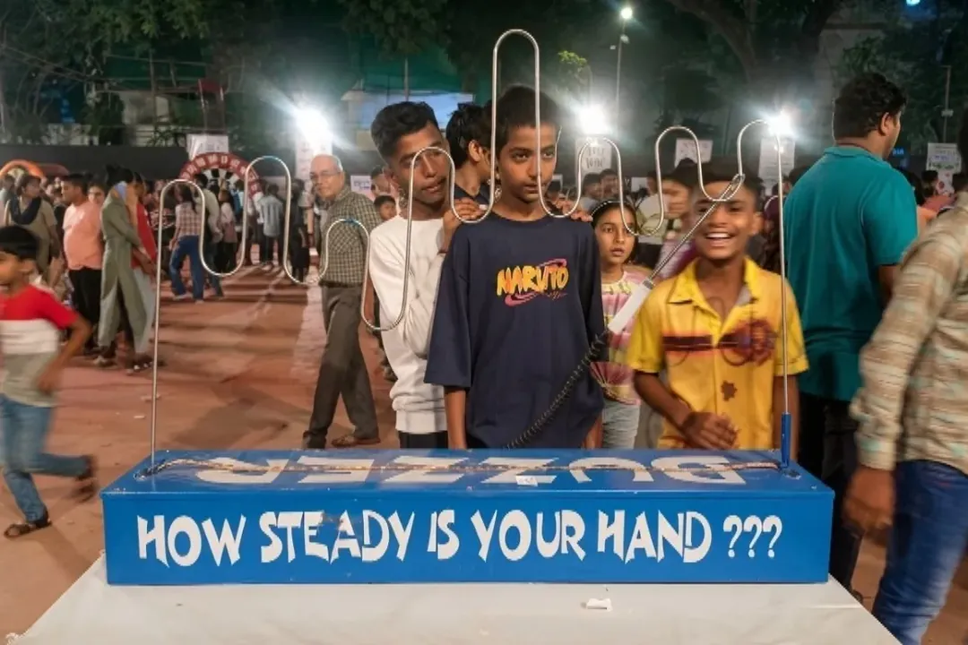 Guests at a buzz wire game labelled How steady is your hand