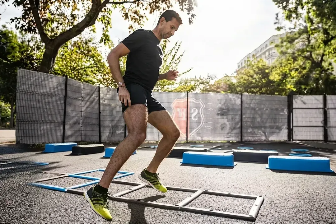 Participant running through an agility ladder and hurdles on an outdoor course