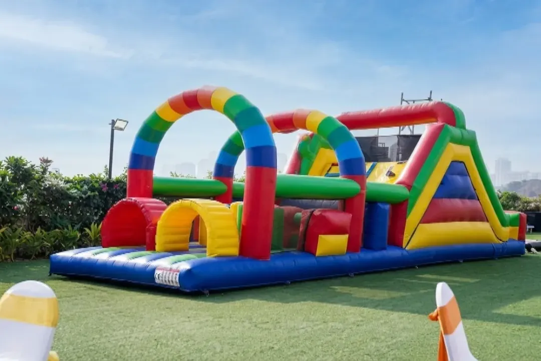 Colourful inflatable obstacle course with arches and a slide on grass