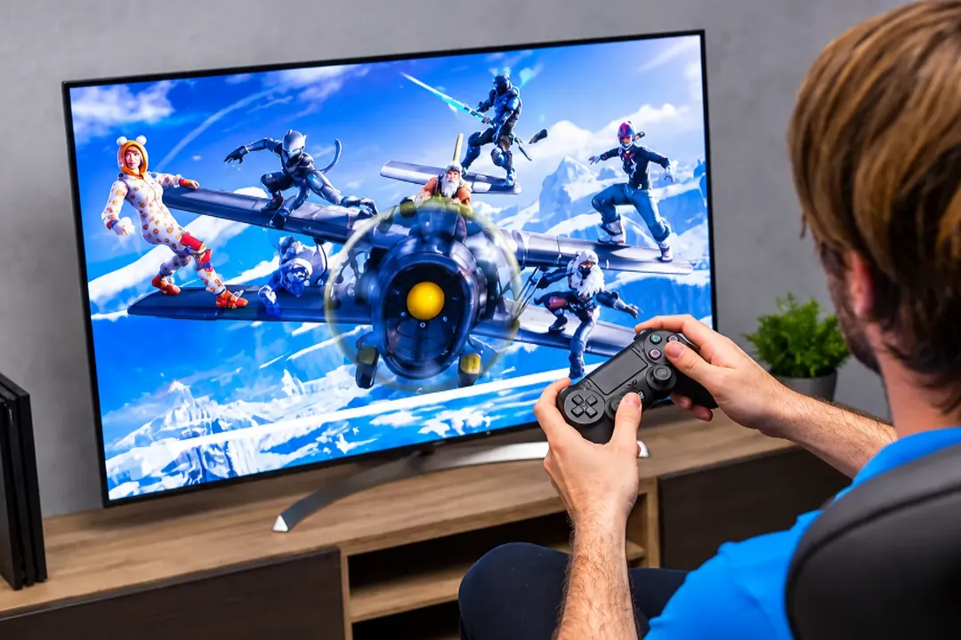 Person holding a game controller while playing on a big screen