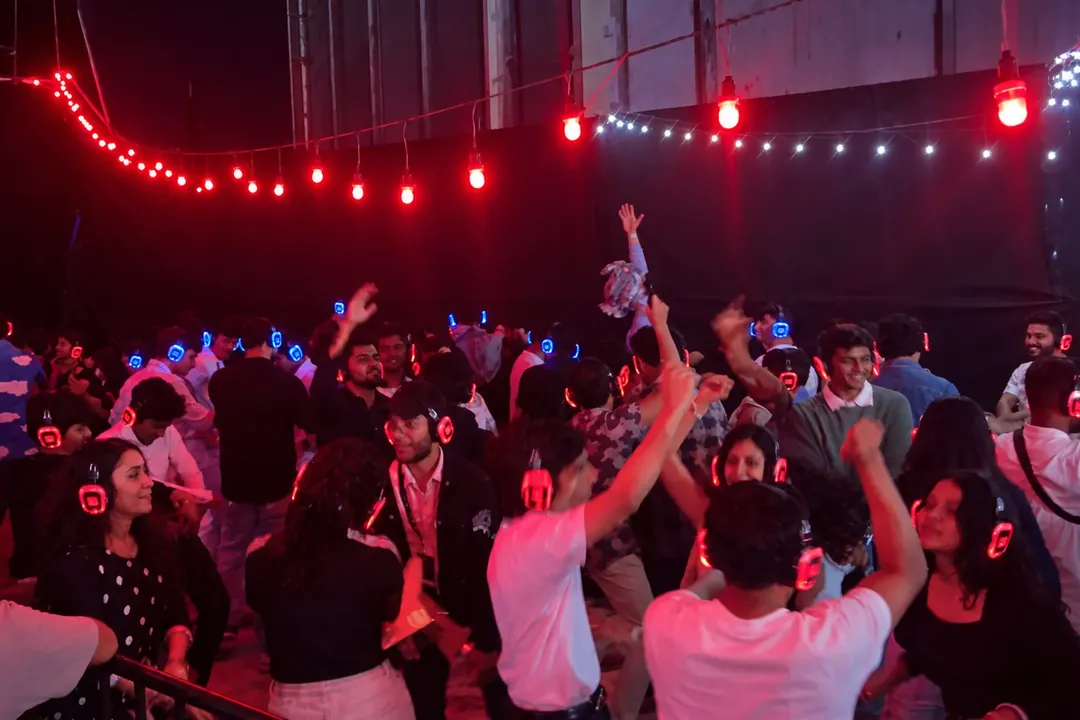 Silent disco crowd with arms raised under red lights