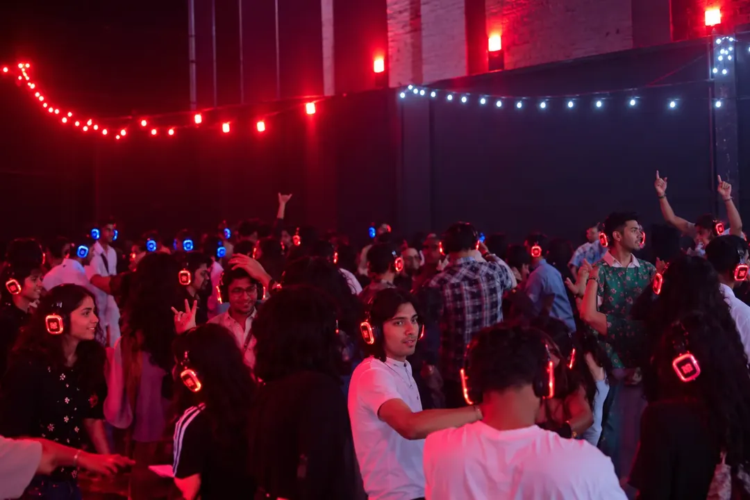 Guests dancing at an indoor silent disco with headphones glowing red and blue